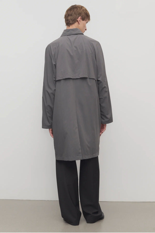 Back view of grey cobalt men's hesper coat on model wearing black pants and boots, against a white background.