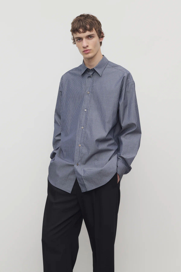 Front view of blue/white men's miller stripe shirt on model wearing black trousers, against a white background.