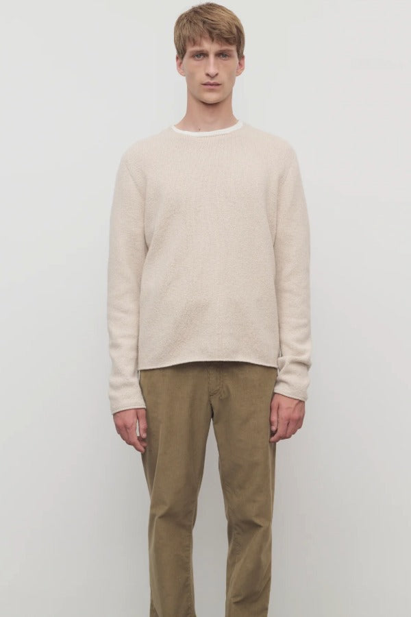 Front view of ecru nikola sweater on model wearing khakis, against a white background.
