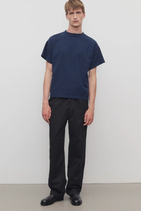 Front view of black sankuro pant on model wearing navy t-shirt, against a white background.