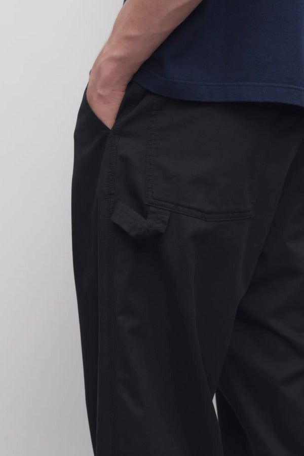 Back closeup view of black sankuro pant on model wearing navy t-shirt, against a white background.