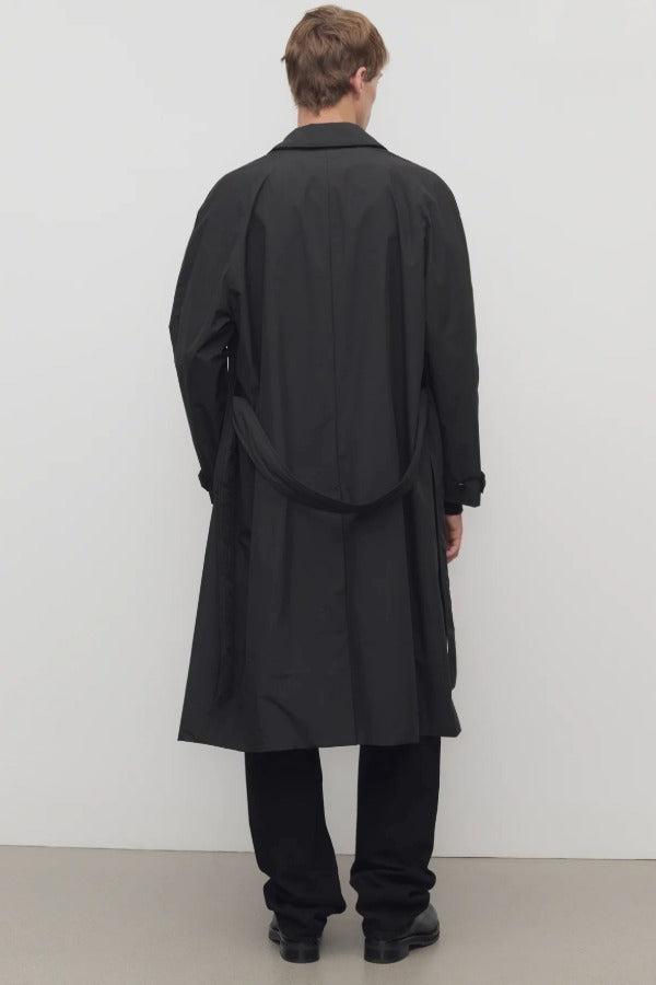 Back view of tarian coat on model wearing black pants and boots, against a white background.