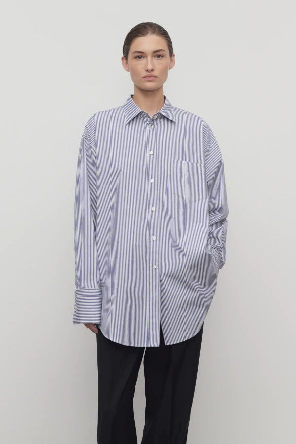 Front view of white and blue Ment shirt on model wearing black trousers, against a white background.