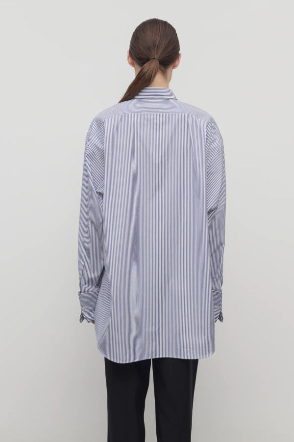Back view of white and blue Ment shirt on model wearing black trousers, against a white background.