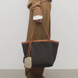 Front view of brown park tote three canvas on model wearing camel pants, sweater and boots, against a white background.