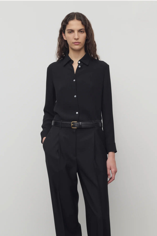 Front view of black petra shirt on model wearing black trousers, against a white background.