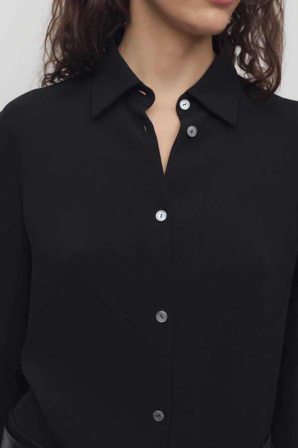 Front closeup view of black petra shirt on model, against a white background.