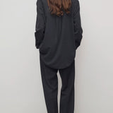 Back view of black relian pant on model wearing black shirt and heels, against a white background.