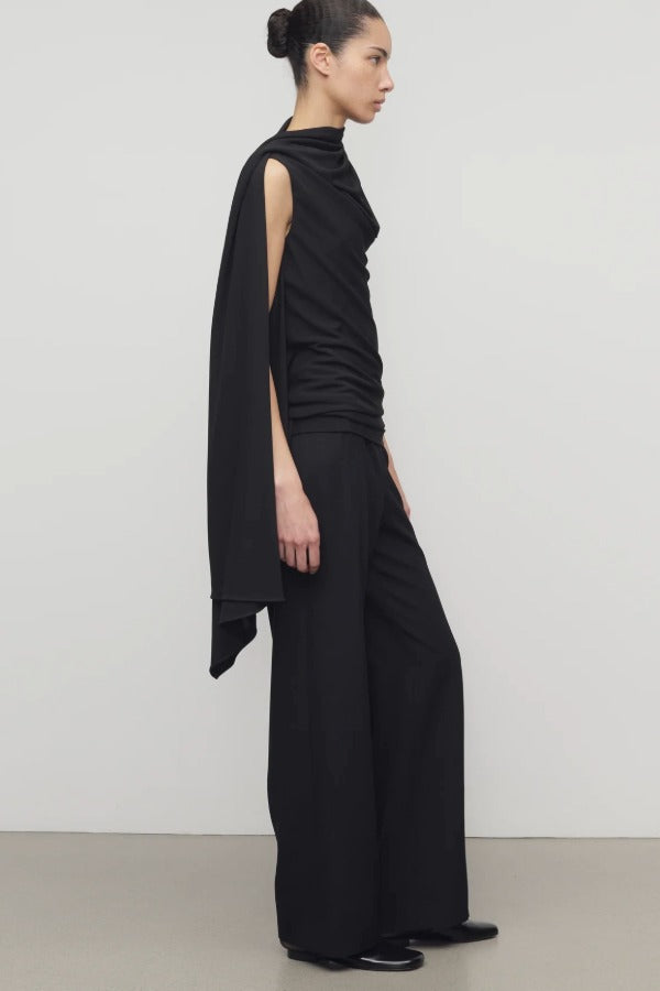 Side view of black roger pant on model wearing black top and heels, against a white background.