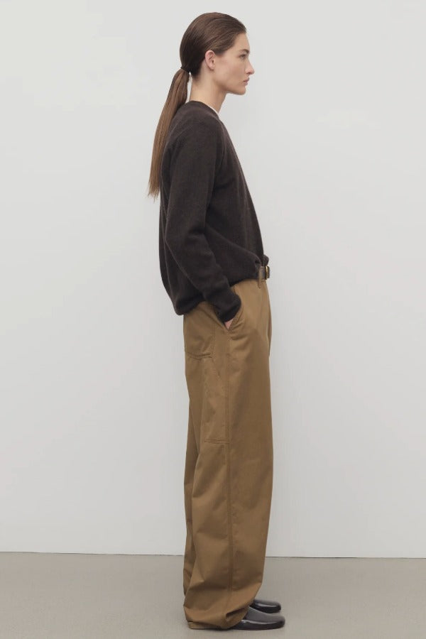 Side view of dark sand sharka pant on model wearing black top, against a white background.