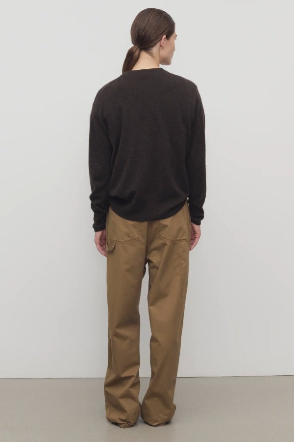 Back view of dark sand sharka pant on model wearing black shirt, against a white background.