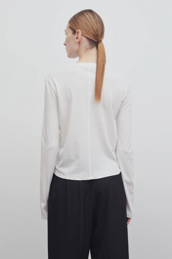 Back view of white sherman t-shirt on model wearing black trousers, against a white background.