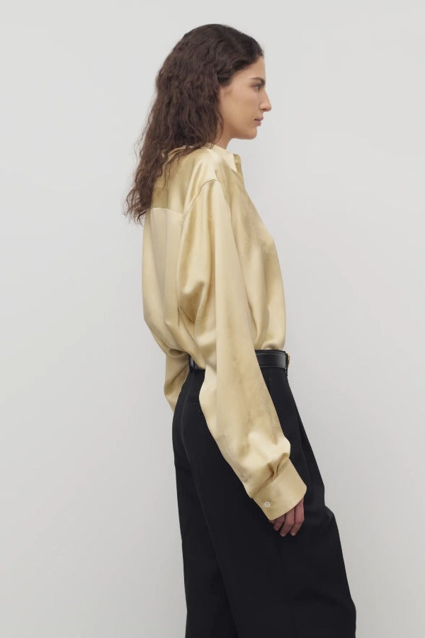 Side view of sand takara shirt on model wearing black pants, against a white background.