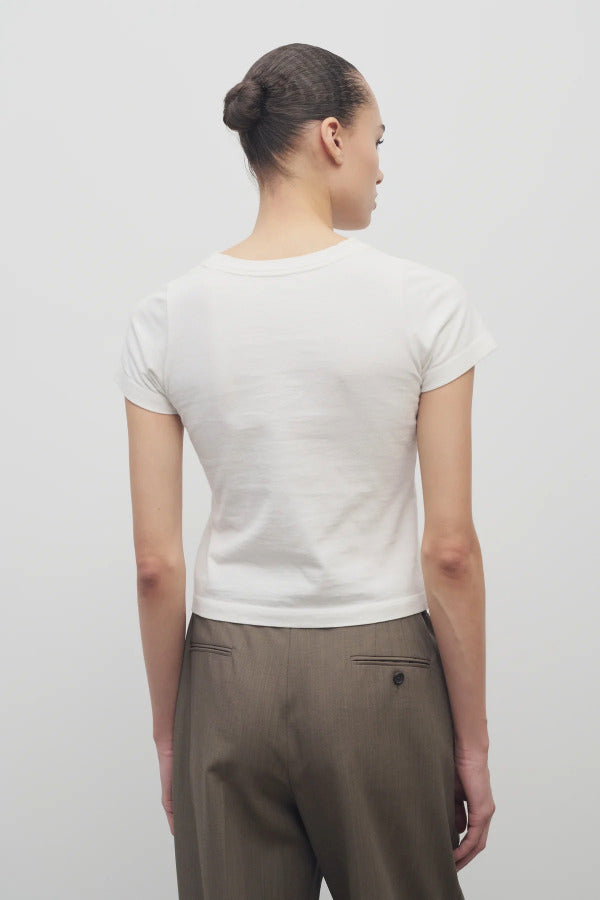Back view of white tori top on model wearing khaki trousers against a white background.