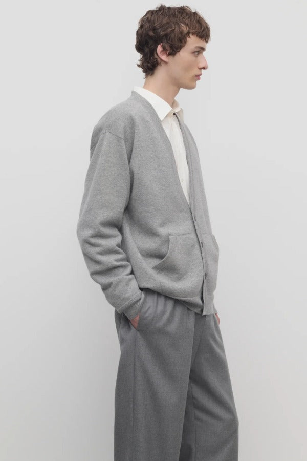 Side view of grey melange vonn cardigan on model wearing grey trousers and a white shirt, against a white background.
