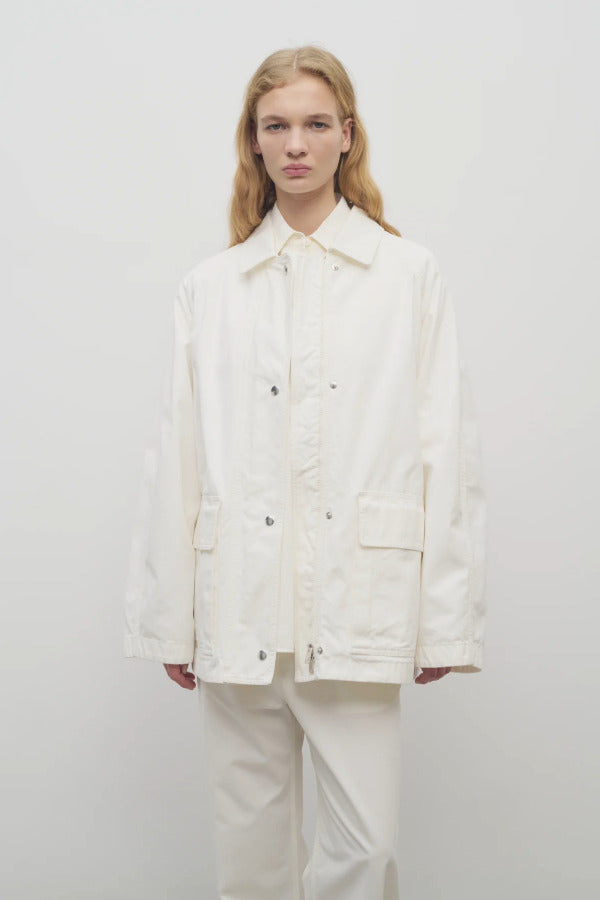 Front view of white button down elodianna jacket on model wearing white shirt and white trousers on white background.