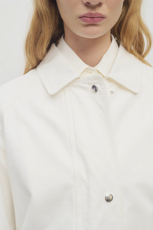 Front closeup view of white button down elodianna jacket on model wearing white shirt, against a white background.