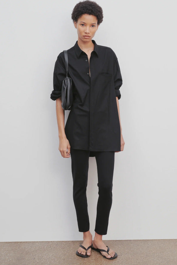 Front view of black woolworth pant on model wearing black tunic top and black sandals against a white background.