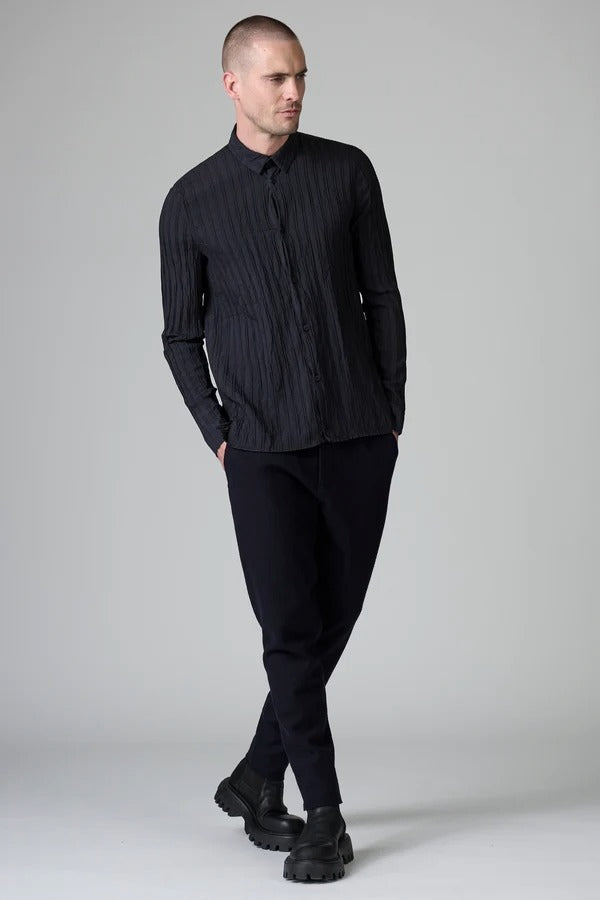 Front view of blue loose fit striped shirt on model wearing black pants, against a grey background.