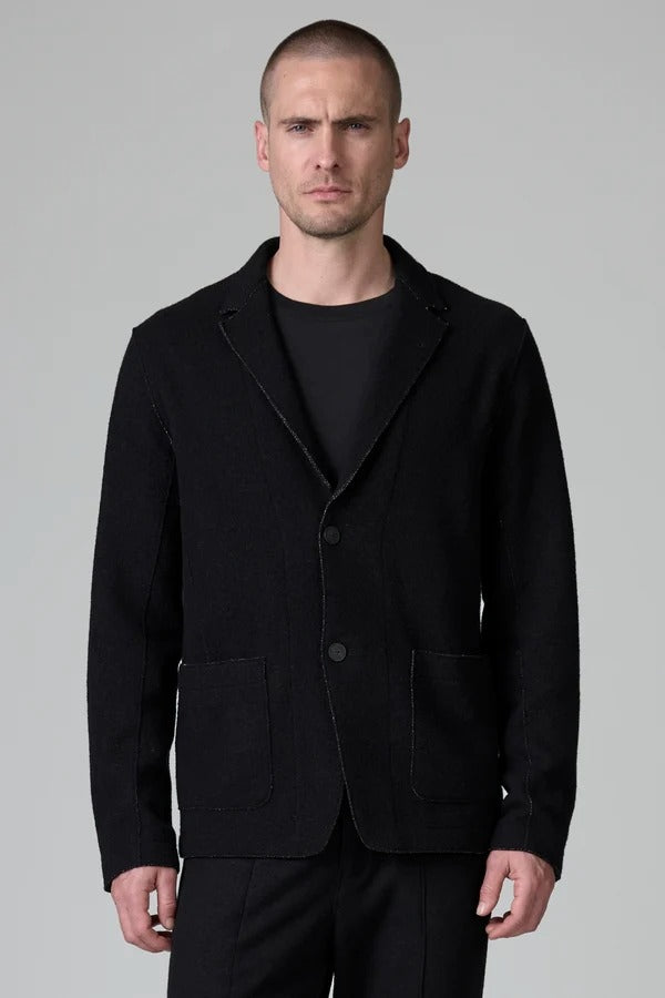 Front view of black/brown regular fit jacket on model wearing black pants, against a grey background.
