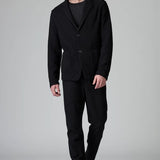 Front view of black/brown regular fit jacket on model wearing black pants, against a grey background.