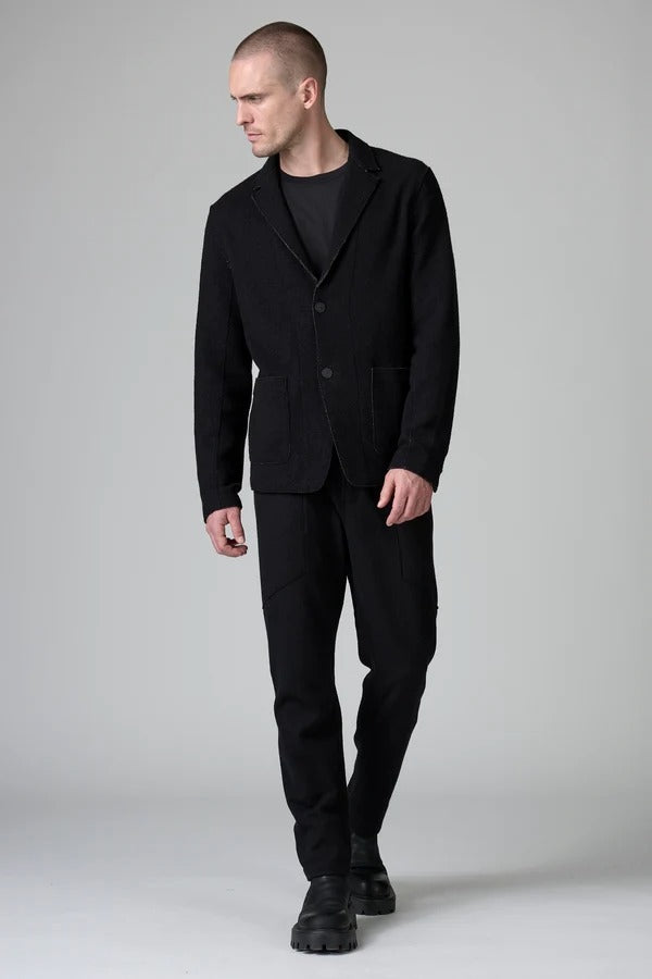 Front view of black/brown regular fit jacket on model wearing black pants, against a grey background.