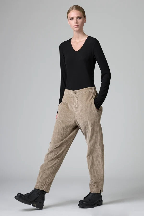 Front view of camel regular fit trousers on model wearing black top and boots, against a grey background.
