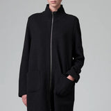 Front view of black/anthracite straight coat on model wearing black pants, against a grey background.