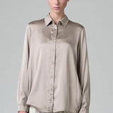 Front view of stone silk satin regular fit shirt on model wearing chalk pants, against a grey background.