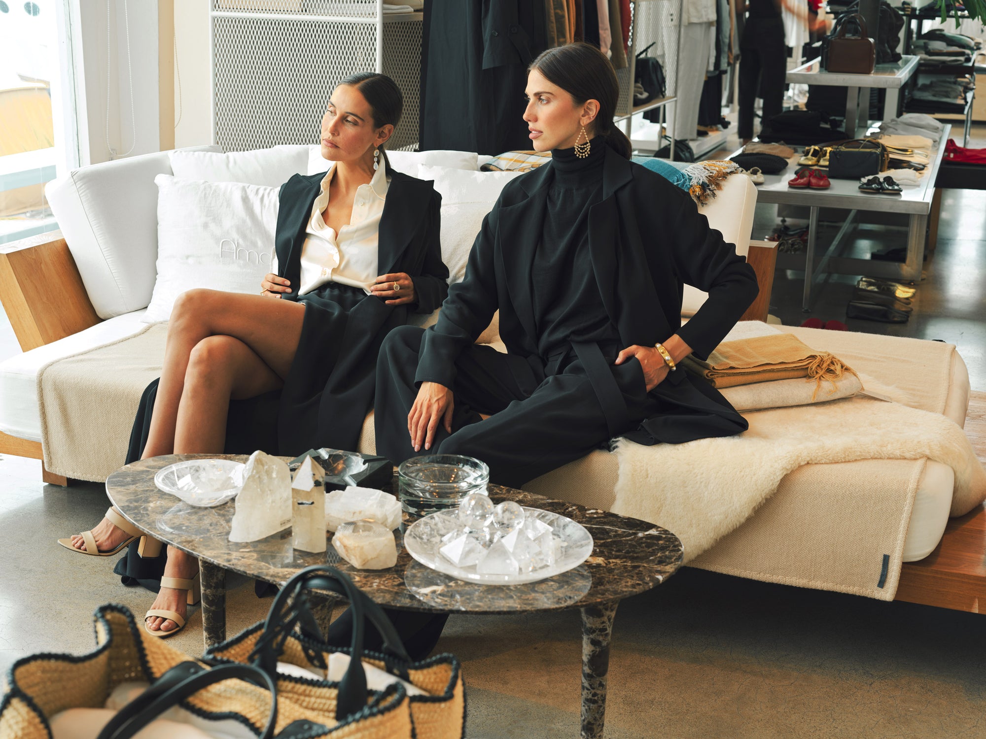 Two women sitting on a couch in a stylish living room with a coffee table in front of them.