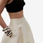 Side view of ivory callum persimmon skirt on model wearing black bralette, against a white background.