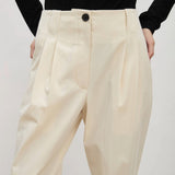 Front view of ivory raine pants on model wearing black shirt, against a white background.