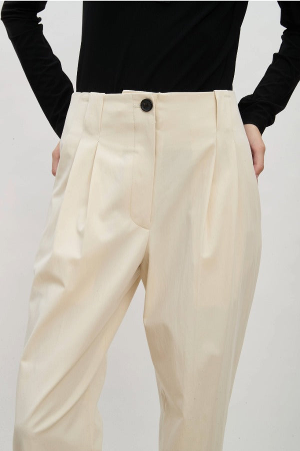 Front view of ivory raine pants on model wearing black shirt, against a white background.