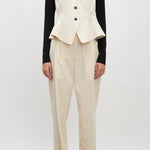 Front view of ivory raine pants on model wearing black shirt, ivory vest and brown loafers, against a white background.