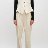 Front view of ivory raine pants on model wearing black shirt, ivory vest and brown loafers, against a white background.