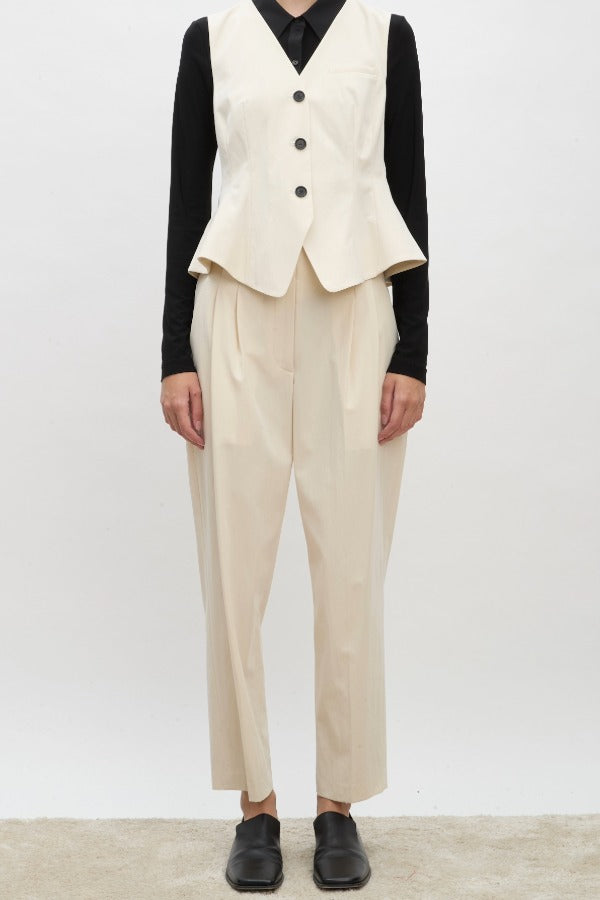 Front view of ivory william vest on model wearing ivory trousers, a black shirt and brown loafers, against a white background.