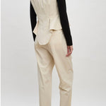 Back view of ivory william vest on model wearing ivory trousers, black shirt and brown loafers, against a white background.