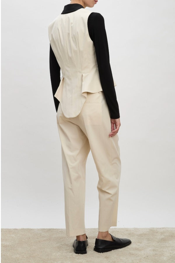 Back view of ivory william vest on model wearing ivory trousers, black shirt and brown loafers, against a white background.