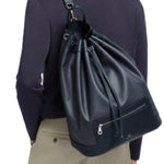 Front view of navy shoulder bag on model wearing khaki trousers and navy shirt on white background.