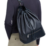Front view of navy shoulder bag on model wearing khaki trousers and navy shirt on white background.