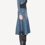 Side view of denim cropped jacket on model wearing black bodysuit, denim skirt and boots, against a white background.