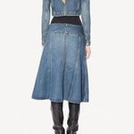 Back view of denim cropped jacket on model wearing black bodysuit, denim skirt, and boots, against a white background.