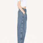 Side view of blanc cropped t-shirt on model wearing jeans and heels, against a white background.