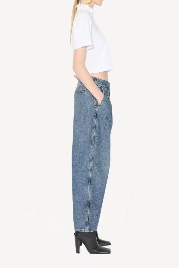 Side view of blanc cropped t-shirt on model wearing jeans and heels, against a white background.