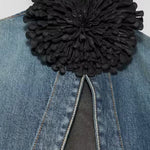 Front view of noir leather flower choker on model wearing jean jacket, against a white background.
