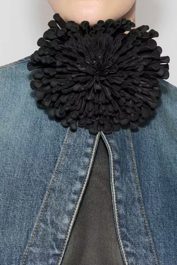 Front view of noir leather flower choker on model wearing jean jacket, against a white background.