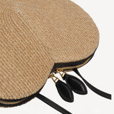 Side closeup view of the natural heart bag in straw on white background, with no model shown.