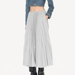 Front view of gris souris pleated skirt on model wearing jean jacket and boots, against a white background.