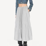 Front view of gris souris pleated skirt on model wearing jean jacket and boots, against a white background.
