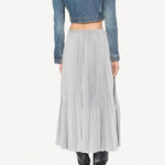 Back view of gris souris pleated skirt on model wearing jean jacket and boots, against a white background.